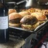 Hamburgers faits maison sur une plaque de four frites en arrière plan et bouteille de Pécharmant l'Ambroisie en premier plan