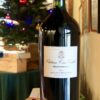 Bouteille de vin d'un volume de 5 litres posée sur une caisse en bois décorée d'un ruban rouge et sapin de Noël décoré en arrière plan